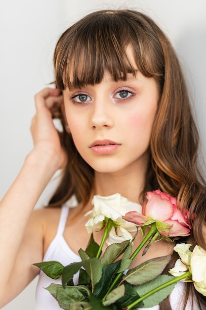 Klein mooi meisje in roze houdt het boeket rozen. Close-up van de bloemen en het gezicht, kleine ballerina met een boeket