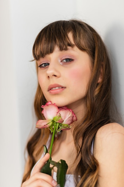 Klein mooi meisje in roze houdt het boeket rozen vast. sluit de bloemen en het gezicht, kleine ballerina met een boeket. mooi klein meisje met roze roos