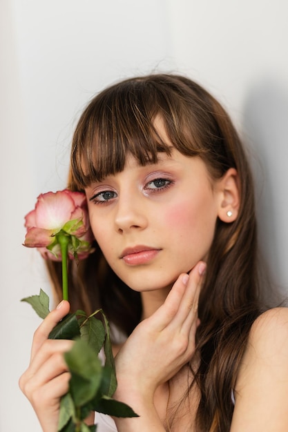 Klein mooi meisje in roze houdt het boeket rozen vast. Sluit de bloemen en het gezicht, kleine ballerina met een boeket