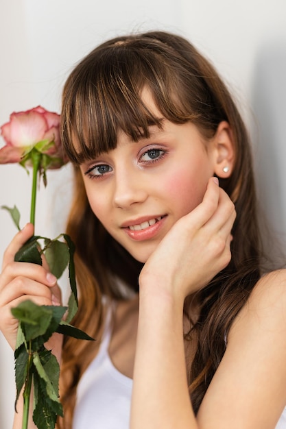 Klein mooi meisje in roze houdt het boeket rozen vast Sluit de bloemen en kijk kleine ballerina aan met een boeketglimlach