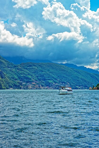 Klein passagiersschip aan de promenade van het luxe resort Lugano aan het meer van Lugano en de bergen van de Alpen, kanton Ticino, Zwitserland.