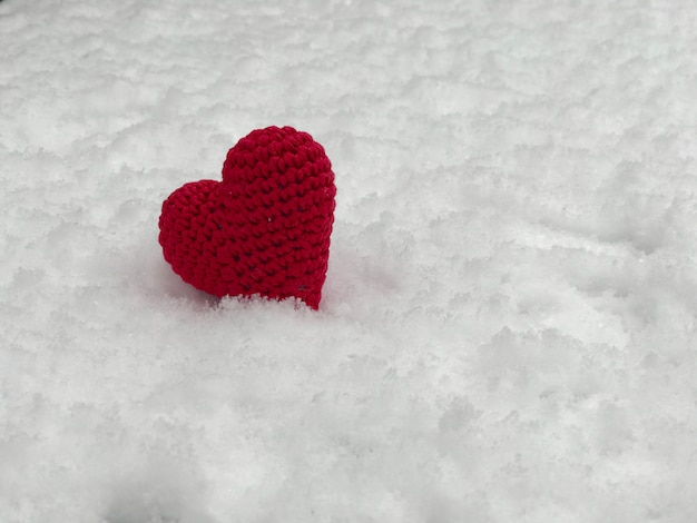 Foto klein rood gebreid hart die op de witte sneeuw liggen