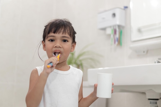 Klein schattig babymeisje dat haar tanden schoonmaakt met een tandenborstel in de badkamer