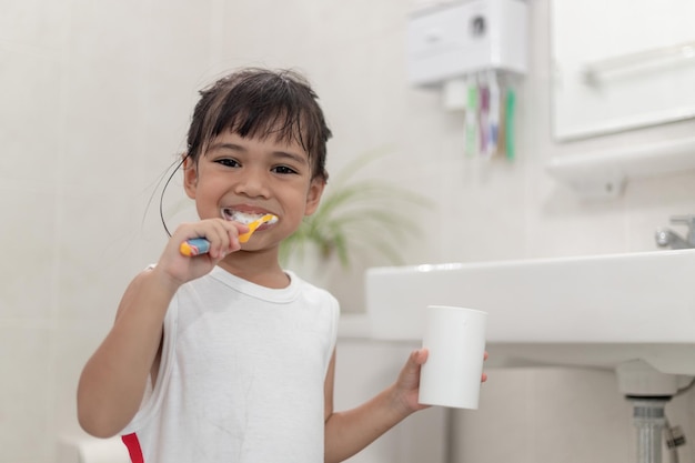 Klein schattig babymeisje dat haar tanden schoonmaakt met een tandenborstel in de badkamer