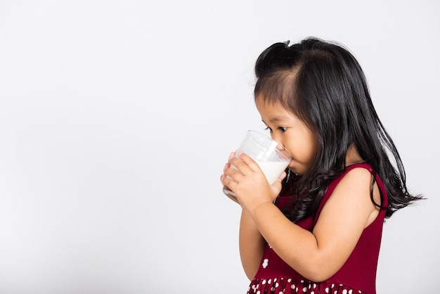 Klein schattig meisje 34 jaar oud glimlach met melkglas hij drinkt witte melk