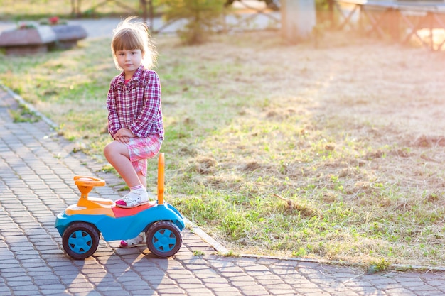 Klein schattig meisje buitenshuis met een speelgoedauto op een zonnige dag