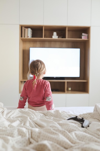 Klein schattig meisje dat thuis televisie kijkt