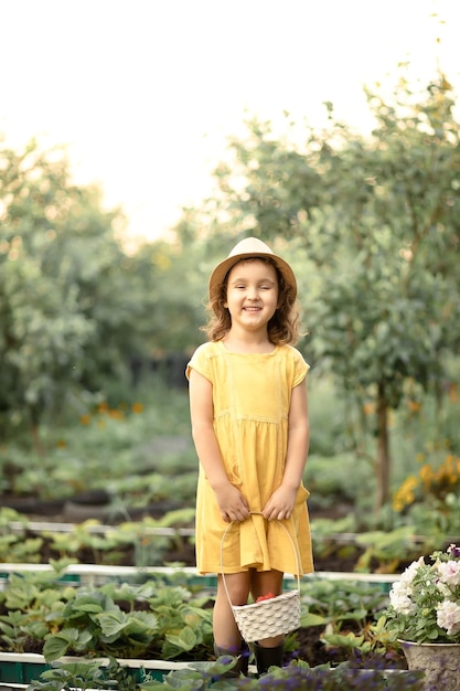 Klein schattig meisje dat verse rijpe aardbeien plukt in witte backet op fruitboerderij of tuin