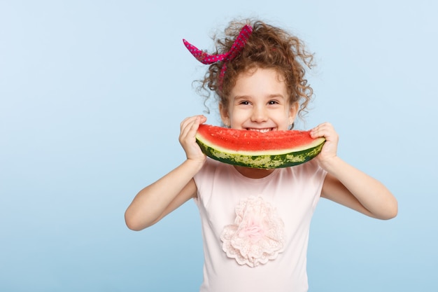 Klein schattig meisje glimlachend en watermeloen eten