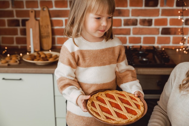 Klein schattig meisje in de keuken, bakt een zoete taart met jam.