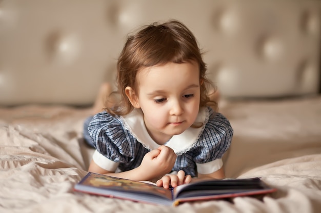 Klein schattig meisje in een retro jurk lezen van een boek.