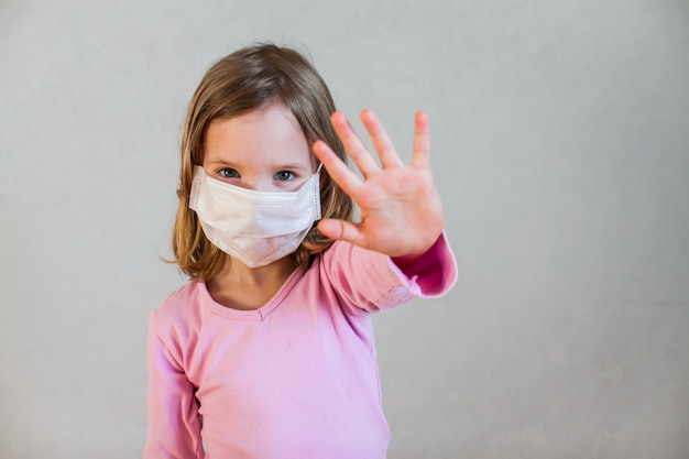 Klein schattig meisje in een witte medische masker