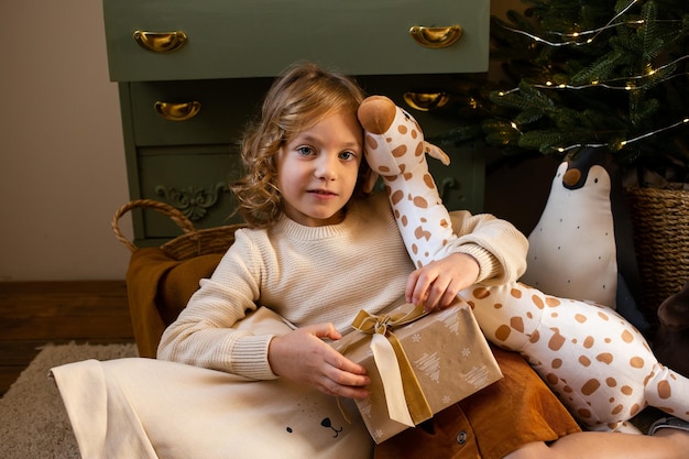 Klein schattig meisje in kersthuis met huidige geschenkdoos in haar handen