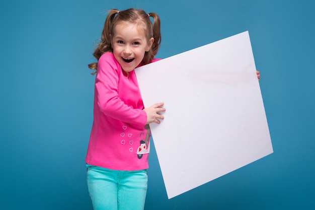 klein schattig meisje in roze shirt met aap en blauwe broek houden lege blanco plakkaat