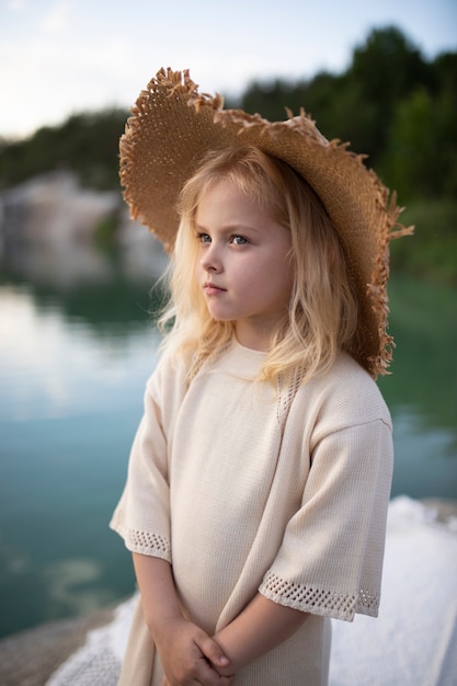 Klein schattig meisje in stijlvolle kleding in een natuurlandschap