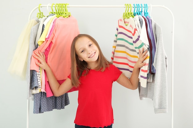 Klein schattig meisje kiest kleding in kleedkamer