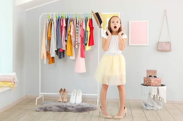 Klein schattig meisje kiest kleding in kleedkamer