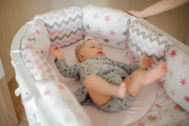 Klein schattig meisje liggend in haar gezellige bed in de grijze jurk