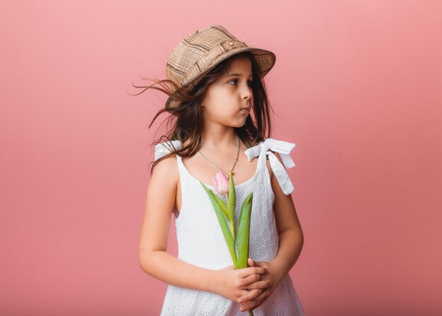 Klein schattig meisje met een boeket tulpen op een roze achtergrond Gelukkige vrouwendag Plaats voor tekst Levendige emoties 8 maart