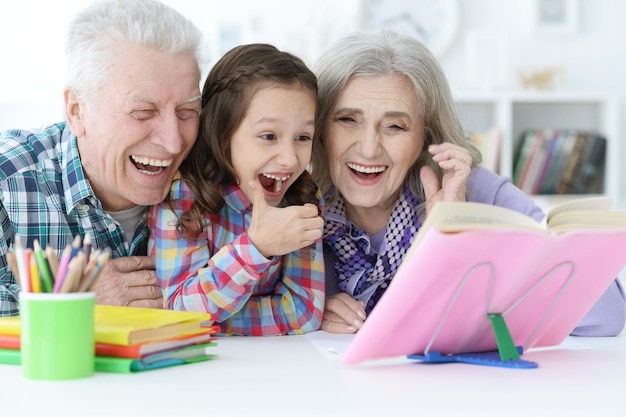 Klein schattig meisje met grootouders die thuis studeren