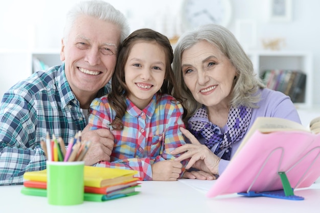 Klein schattig meisje met grootouders die thuis studeren