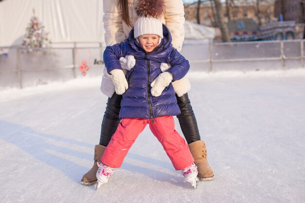 Klein schattig meisje met haar moeder leren schaatsen