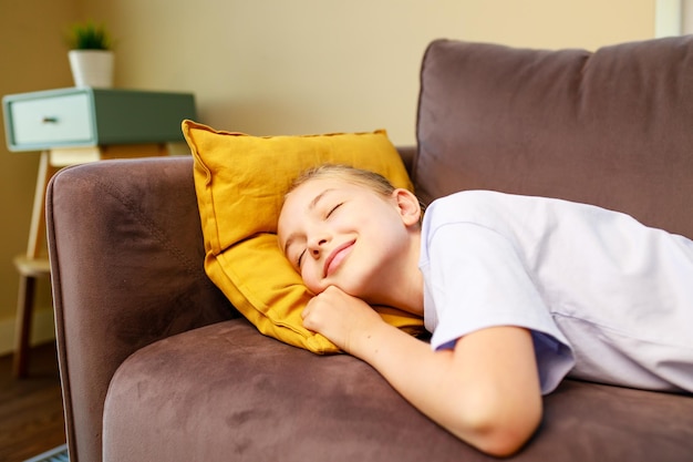 Klein schattig meisje slaapt op de bank na studie op school overdag