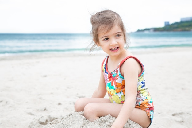 Klein schattig meisje spelen in het zand op het strand aan zee. Zomerentertainment en recreatie.