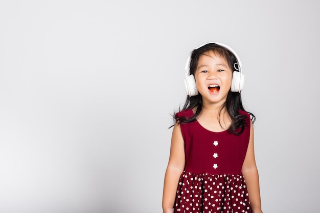 Klein schattig meisje van 3 jaar oud luistert naar muziek in draadloze hoofdtelefoons
