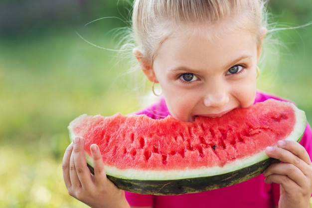 klein schattig meisje van 7 jaar eet een watermeloen