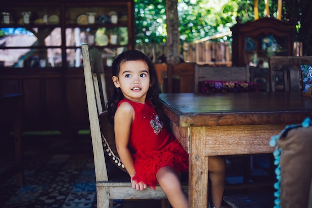 Klein schattig meisje zittend op een stoel aan tafel