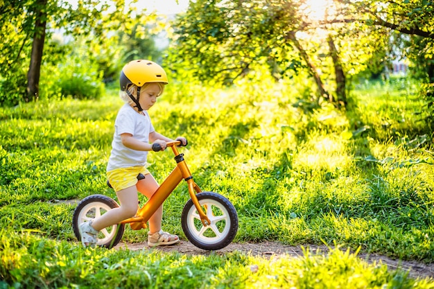 Klein schattig schattig kaukasisch peutermeisje dat plezier heeft met paardrijden oefening balans run fiets duw scooter...