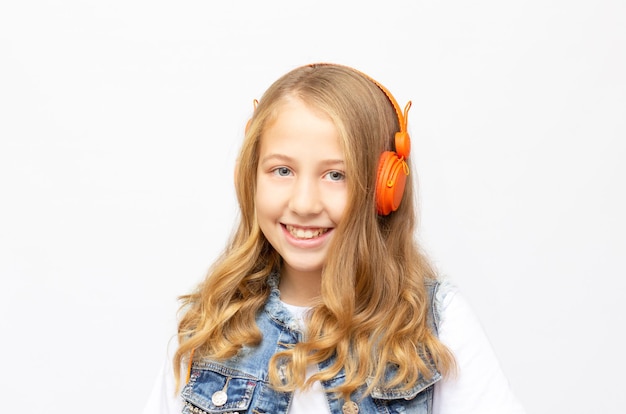 Klein schattig tienermeisje in een oranje koptelefoon