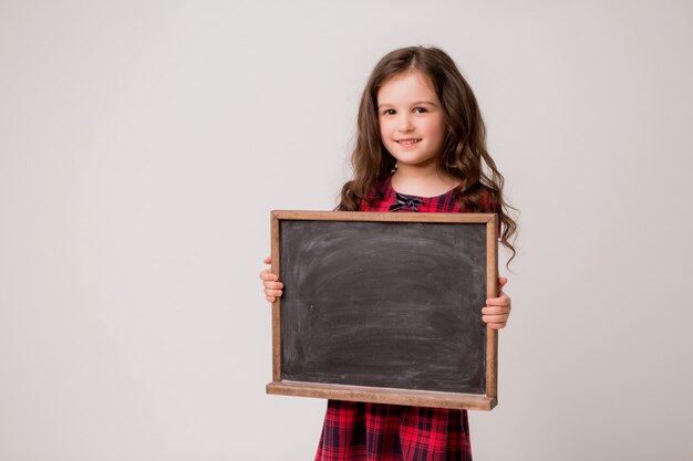 Klein schoolmeisje lachend op lichte achtergrond