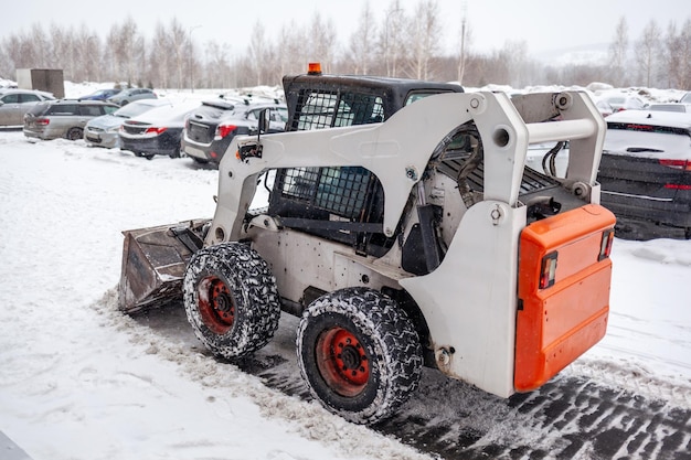 Klein sneeuwruimvoertuig dat sneeuw verwijdert op stadsplein Gele tractor die de sneeuw op straat schoonmaakt