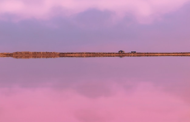 Foto klein stenen huis en zijn reflectie op een wazige roze achtergrond