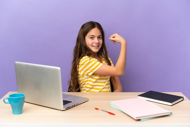 Klein studentenmeisje op een werkplek met een laptop geïsoleerd op een paarse achtergrond die een sterk gebaar doet