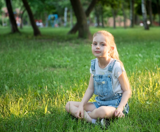 Klein verdrietig meisje zittend in het park op het gras