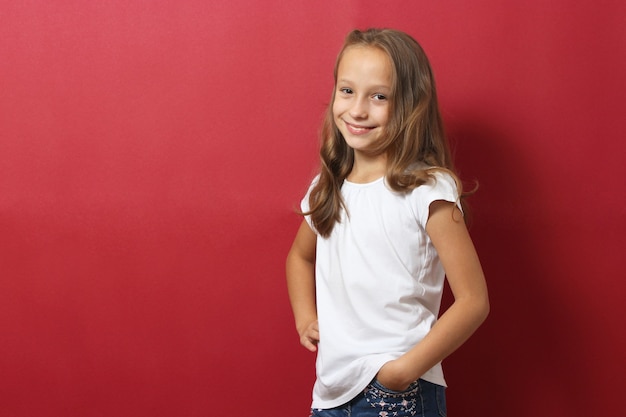 Klein vrolijk lachend meisje in modieuze kleding op een gekleurde achtergrond