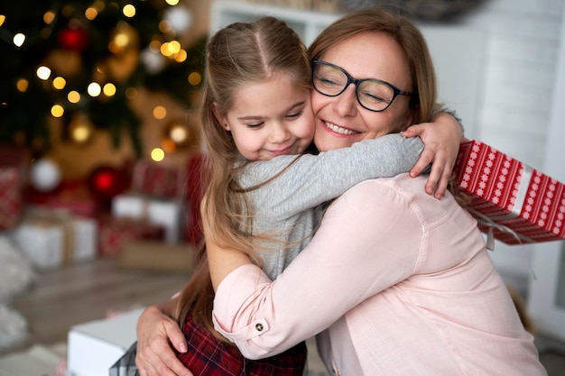 kleindochter die haar grootmoeder omhelst in de kersttijd