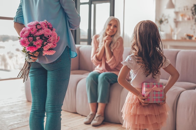 Kleindochter en moeder met cadeautjes achter de rug om een verrassing voor oma te maken