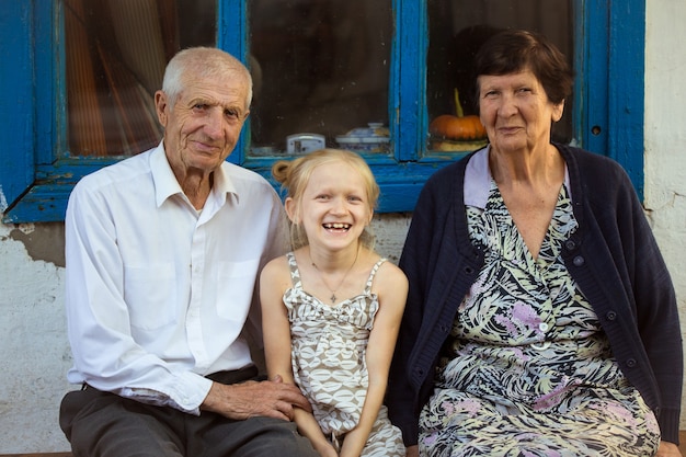 Foto kleindochter omarmen met grootouders die aan de voorkant van het landelijke huis zitten