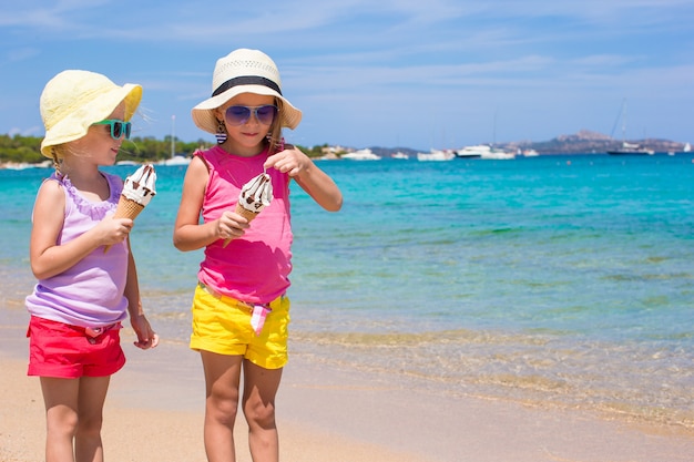 Kleine aanbiddelijke meisjes die roomijs op tropisch strand eten