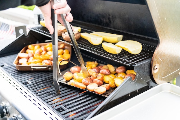 Kleine aardappelen grillen met plakjes knoflook op een buitengasgrill.