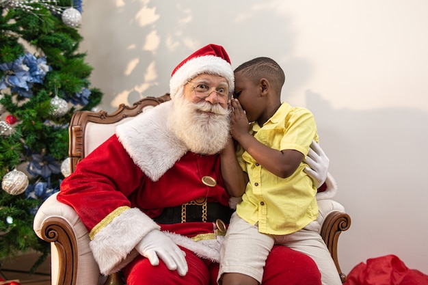 Kleine Afrikaanse jongen die in het oor van de kerstman fluistert