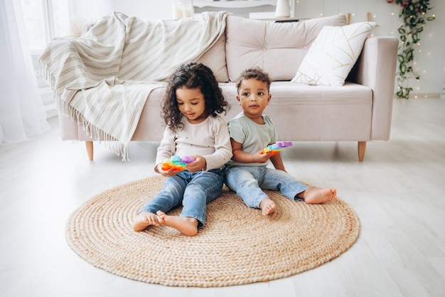 Kleine Afro-Amerikaanse zwarte kinderen die thuis met popspeelgoed op de vloer spelen