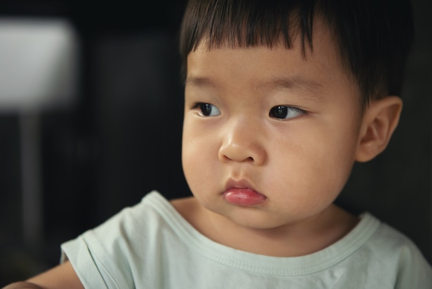 Kleine Aziatische kinderen jongen steenbolk en frons op zwart.