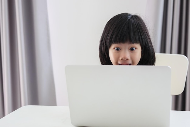 Kleine Aziatische studente studeert online met een laptop thuis
