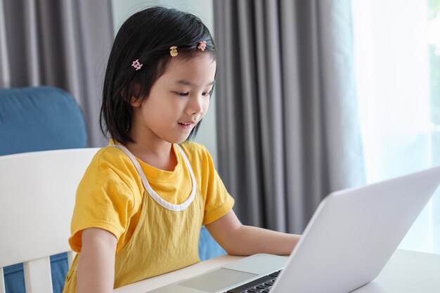 Kleine Aziatische studente studeert online met een laptop thuis