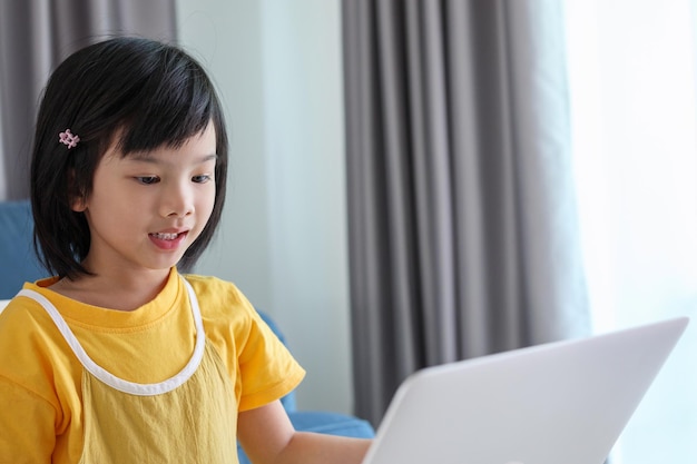 Kleine Aziatische studente studeert online met een laptop thuis